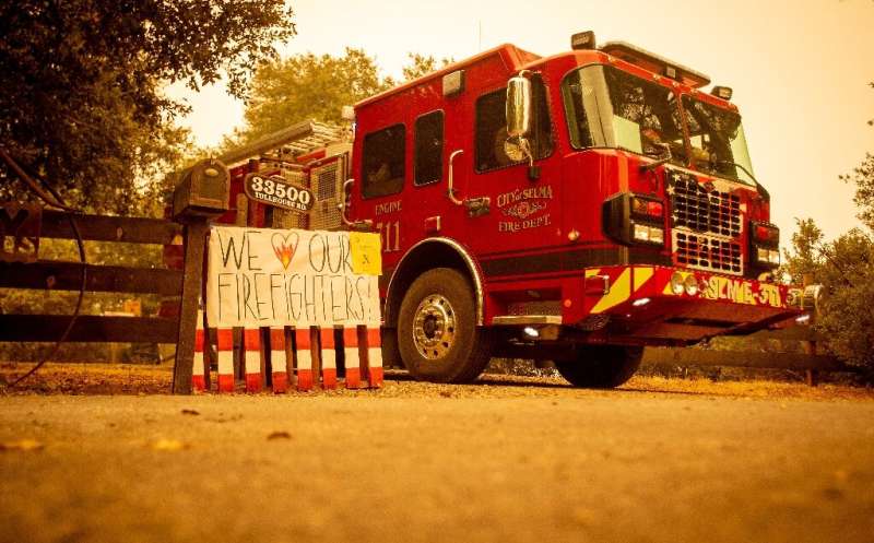 A sign is posted next to a fire vehicle as flames continue to consume the area during the Creek fire in Fresno County, Californi