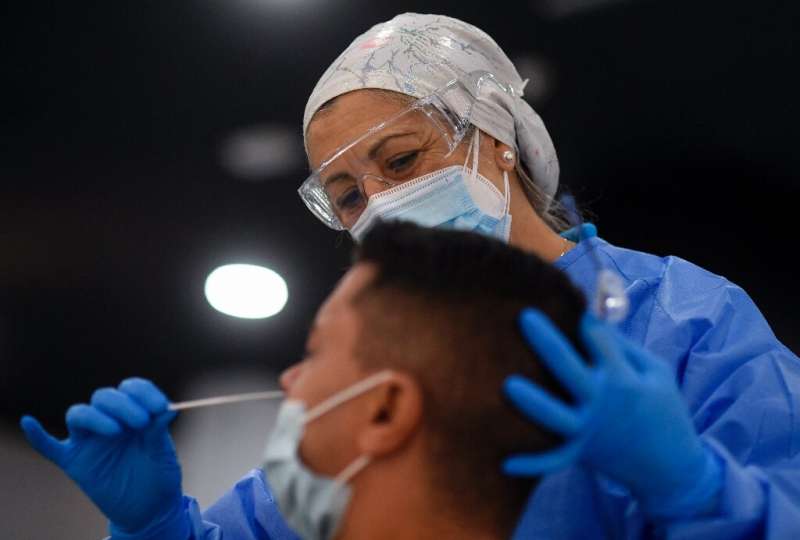 A Spanish medical worker takes a swab sample from a man in Madrid, Spain