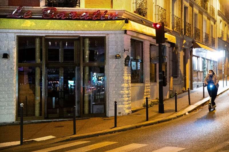 A woman walks by a closed restaurant in France during a second lockdown