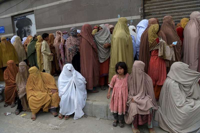 Burqa-clad women in Peshawar wait to collect cash under the governmental Ehsaas Emergency Cash Programme for families in need du