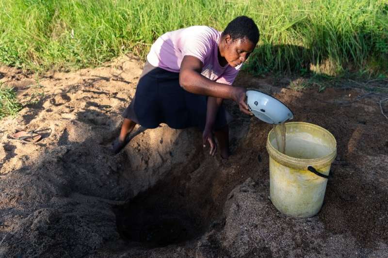 Celia Munhangu scoops through sand in search of water on the dried-up bed of the Mavhaire river in Buhera