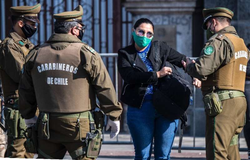 Chilean security forces check a woman's documents as they enforce a total quarantine to prevent the spread of the coronavirus in