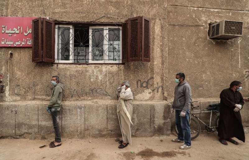 Egyptian men wait outside a centre of non-governmental organisation the Egyptian Food Bank to receive cartons with foodstuffs am