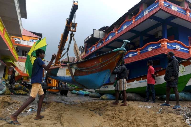Fishermen move their boats as cyclone Nivar approaches the eastern Indian coast