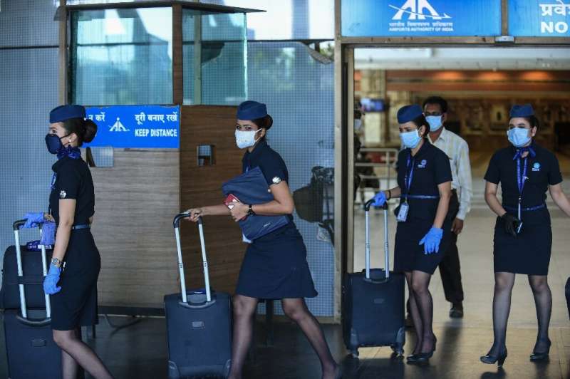 Flight attendants walk out of Sardar Vallabhbhai Patel International Airport in Ahmedabad as domestic flights resume after the g