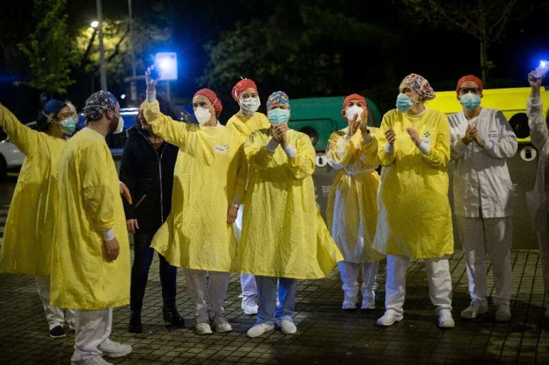 Heathcare workers acknowledge applause outside a hospital in Barcelona