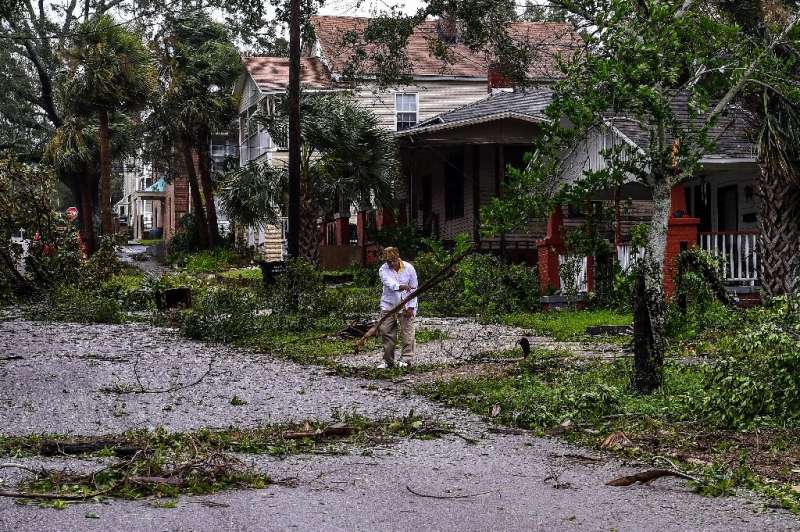 Mark Robinson removes tree branches outside his home in Pensacola, Florida