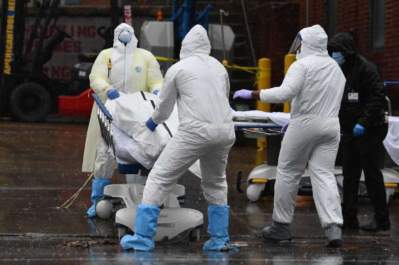 Medical personnel move a body to a refrigerated truck serving as a makeshift morgue at Brooklyn Hospital Center in New York