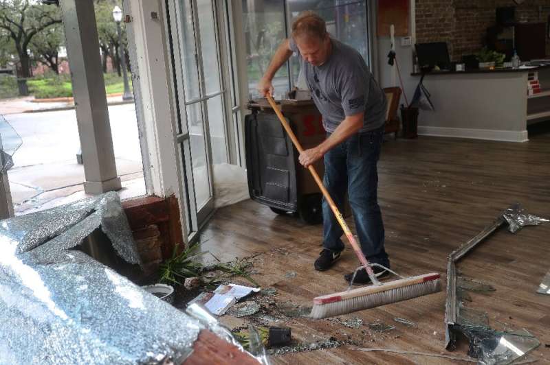 Morgan Griffin cleans up a broken window in the store where he works in Mobile, Alabama, after Hurricane Sally