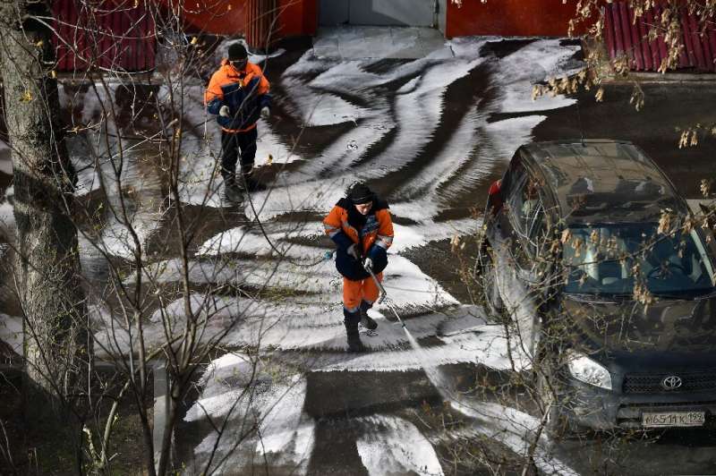 Municipal workers clean and disinfect walkways in a yard in Moscow, during the strict lockdown in Russia
