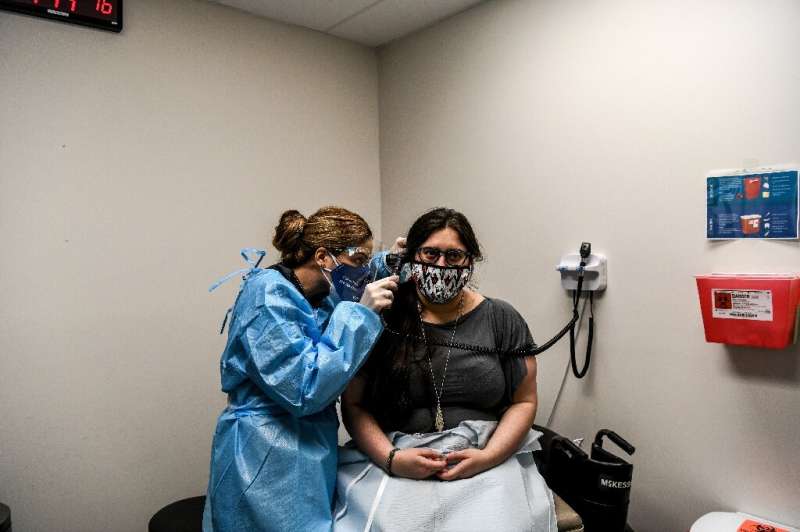 Nelia Sanchez-Crespo (L) examines Heather Lieberman, 28, as she participates in a COVID-19 vaccination study at the Research Cen