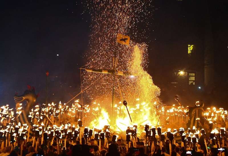 People dressed as Vikings throw flaming torches into their reconstructed longboat at a festival in the Shetland Islands