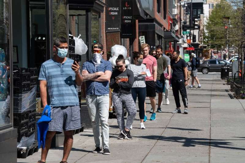 People stand in line to enter a grocery store in Washington, DC amid the coronavirus pandemic