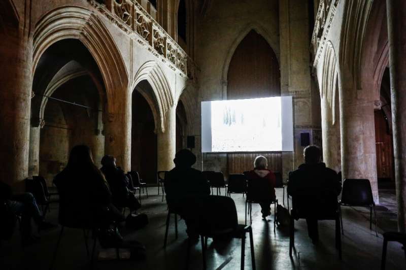 人们观看一部电影，而在法国北部的卡昂的Vieux Saint-Sauveur教堂的社会偏差