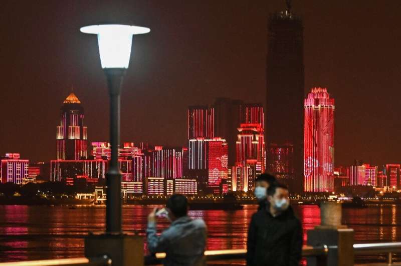 People wearing facemasks walk near the Yangtze River in Wuhan, epicentre of the coronavirus, which reported no new deaths from t