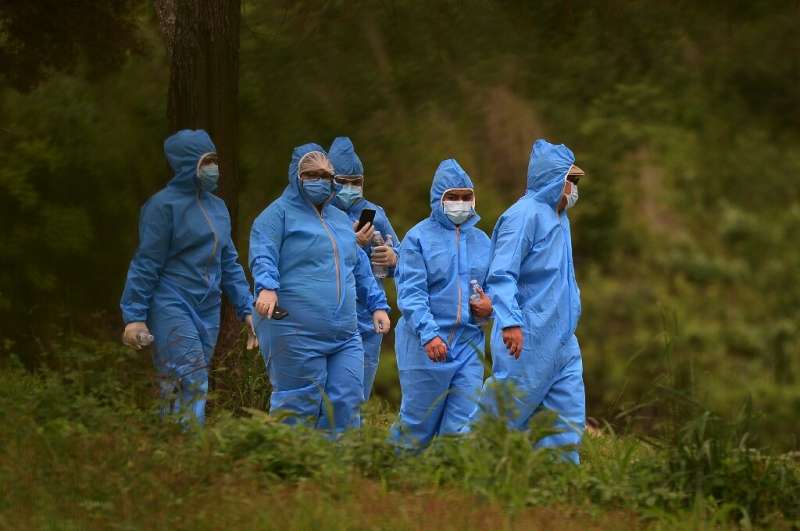 People wear protective suits while attending the burial of a loved one at the annex of the Jardin de Los Angeles cemetery where 