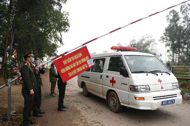 Police allow an ambulance to pass through a checkpoint outside a quarantined area in Vietnam
