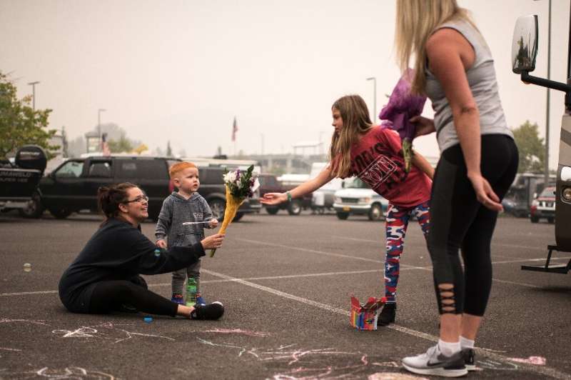 Rebecca Manley and her son, James, accept a bouquet from volunteers handing out flowers at a fire evacuation site set up in the 