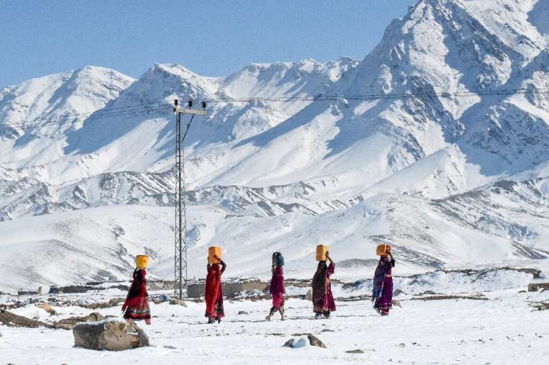 Residents of Khanozai, northwest of Quetta, Pakistan, carry water pots above their heads as they walk home after heavy snowfall