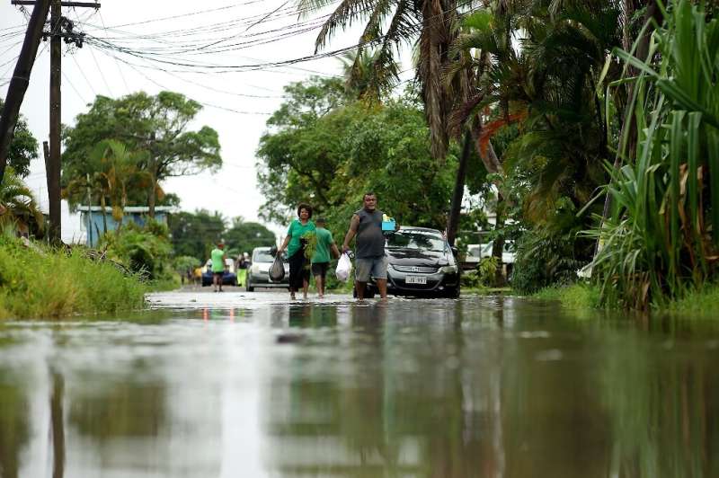 Residents wade through the flooded streets in Fiji's capital city of Suva on December 16, 2020, ahead of super cyclone Yasa