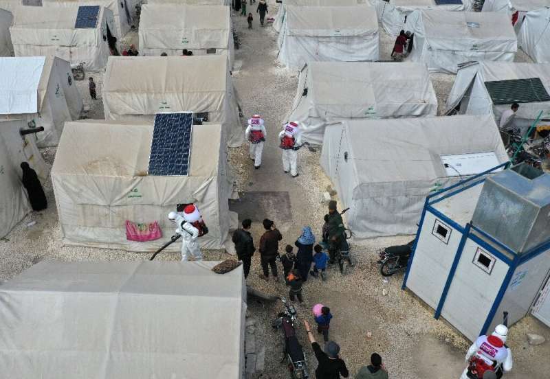 Sanitation workers disinfect a camp for displaced Syrians next to the Idlib municipal stadium