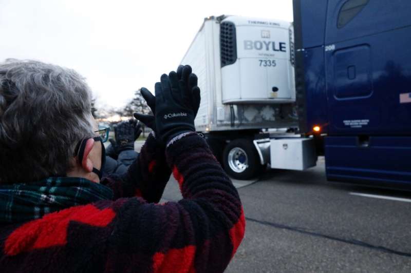 Susan Deur cheers as trucks carrying the first shipment of the Covid-19 vaccine, escorted by the US Marshals Service, leave Pfiz
