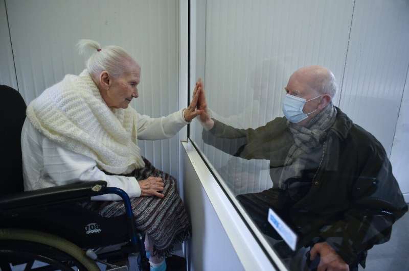 Suzanne Valette, an 88-year-old infected with COVID-19, talks to her son through plexiglass at the Buissonets retirement home in