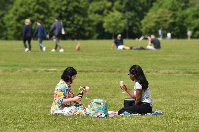 Two women enjoy a drink in the grass in London's Hyde Park, after the were reopened for the first time in months
