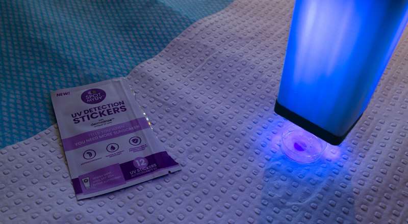 紫外线检测贴纸警告年轻的足球运动员涂抹防晒霜