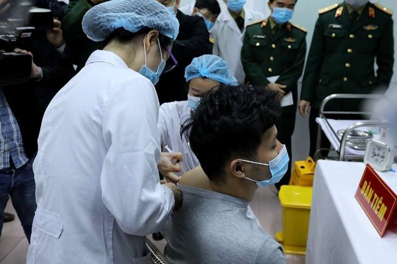 Vietnamese military medical officials administer a shot of the Covid-19 vaccine Nanocovax to a volunteer in Hanoi