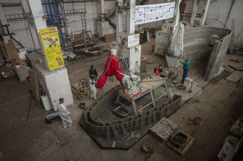 Workers check over the 3D construction, which is being printed from special concrete and is due to float down the river Vltava i