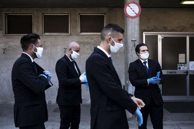 Workers from a funeral home company near Cuneo in northwestern Italy prepare to hold a service for a coronavirus victim