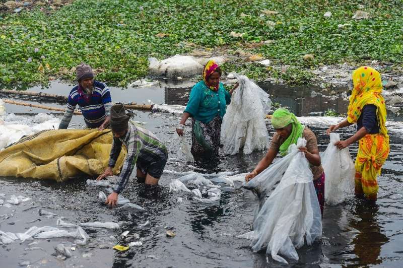 Workers scrub plastic bags used to carry industrial chemicals in the Buriganga river, which has become one of the world's most p