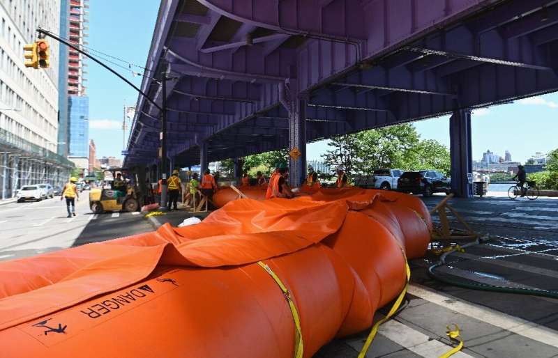 Workers set up temporary plastic flood barriers and sandbags known as 'Tiger Dams' in lower Manhattan to protect the area from f