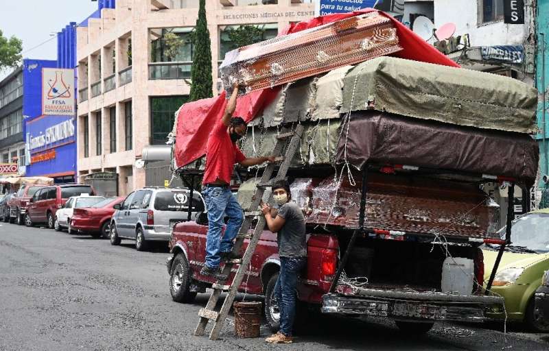 Workers unload coffins from a truck outside a funeral home located in front of the General Hospital in Mexico City