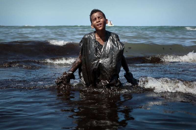 A boy removing oil spilled on Itapuama beach, in Cabo de Santo Agostinho, Pernambuco State, Brazil. After a tw-year investigatio