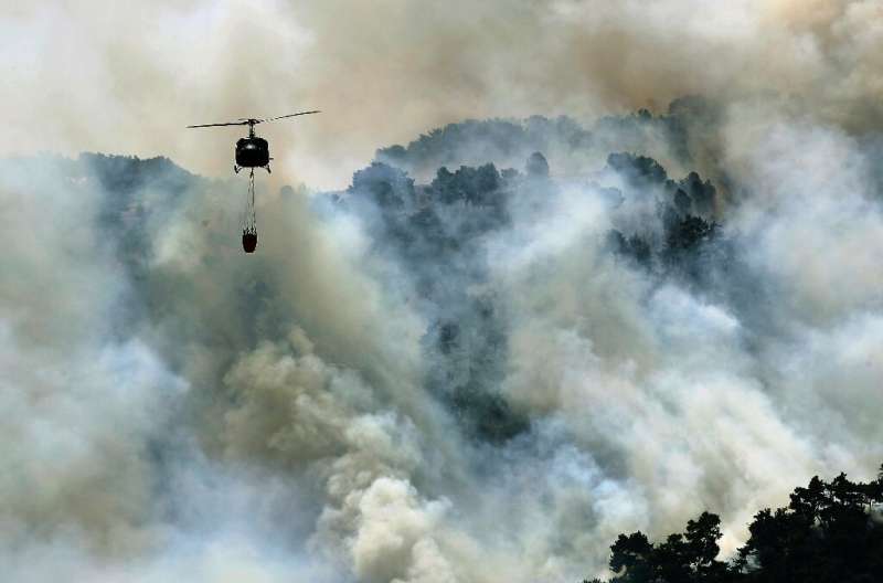 A Lebanese army helicopter drops water on a forest fire in the Qubayyat area of northern Lebanon's remote Akkar region during a 