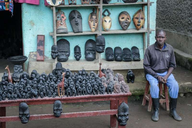 Vietinis vyras prie įėjimo į Ruandos ugnikalnių nacionalinį parką demonstruoja parduodamus suvenyrus