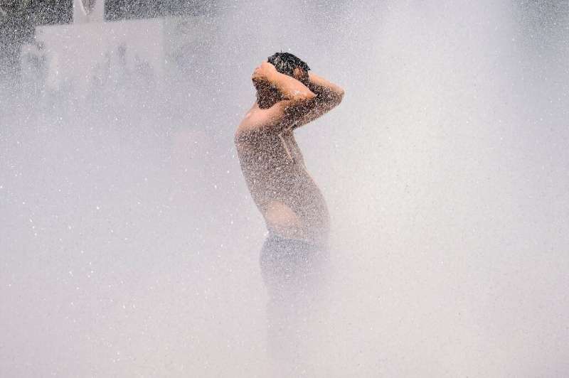 A man cools off in the Salmon Street springs fountain in Portland, Oregon on June 28, 2021, as a heatwave moves over much of the
