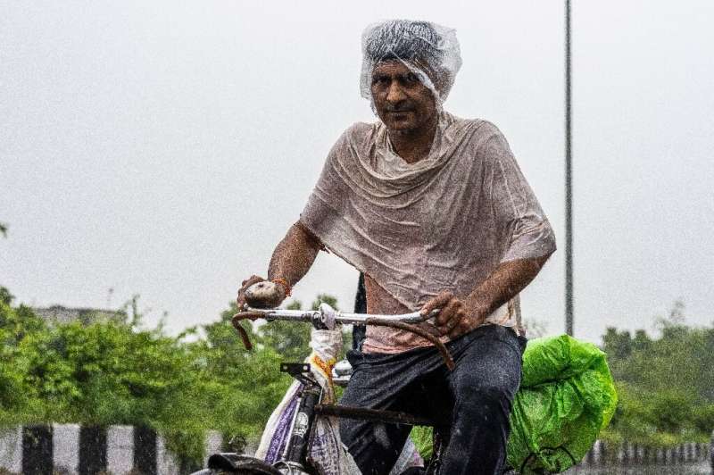 A man rides a bicycle along a street during heavy rain in New Delhi