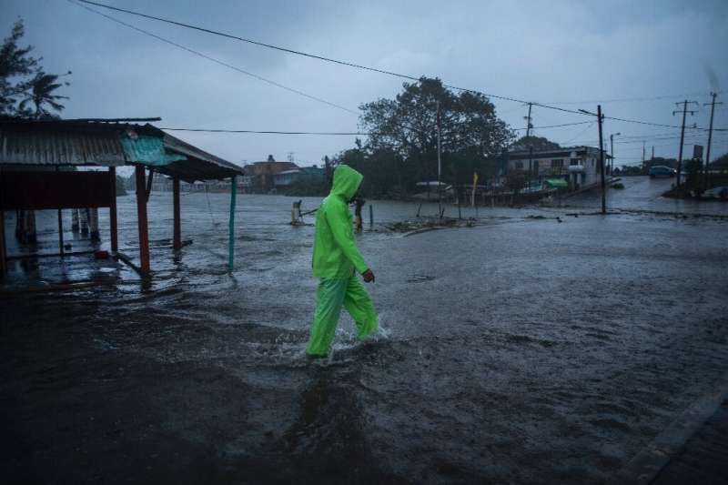 A man walks in a flooded street due to heavy rains caused by Hurricane Grace in Tecolutla in eastern Mexico