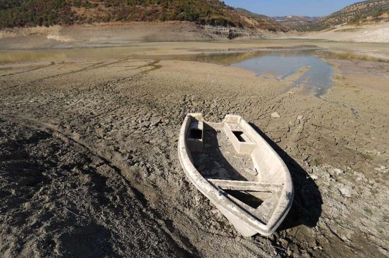 A rowing boat lies grounded on the exposed lake bed of Syria's Duwaysat Dam reservoir after it dried up completely for the first
