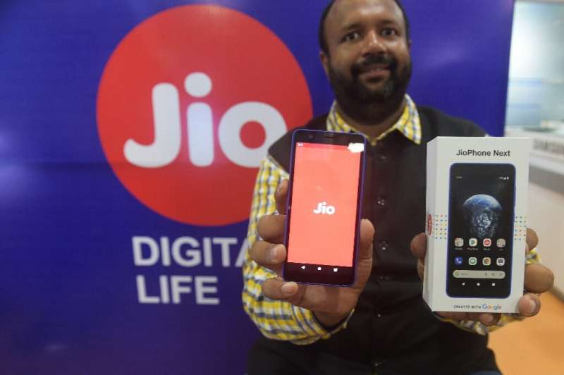 A shopkeeper poses with the new JioPhone Next smartphone in the Indian city of Ahmedabad