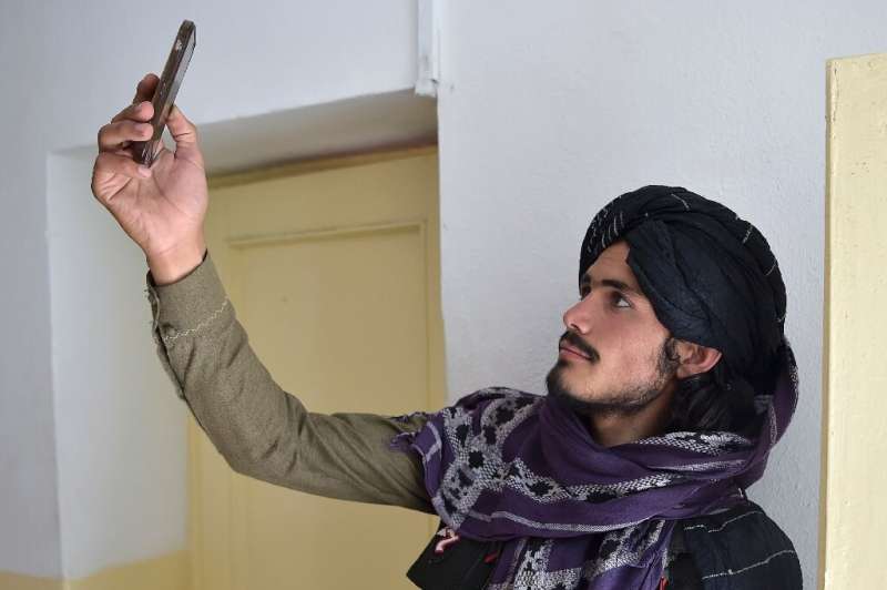 A Taliban fighter searches for a network signal in Ghazni province