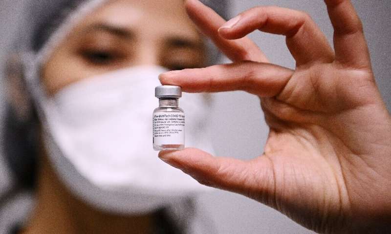A health worker holds a vial containing the Pfizer/BioNTech Covid-19 vaccine in Aulnay-sous-Bois, France
