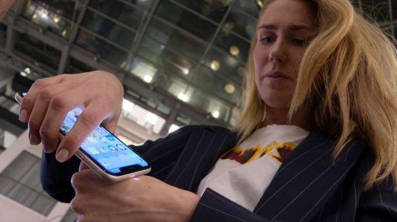 Amanda Back uses her smartphone to scan a microchip implanted in her hand to reveal her health pass