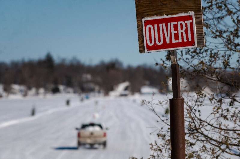 An &quot;Open&quot; sign is seen as a car drives onto the ice road connecting the towns of Pointe-Fortune and Saint-Andre-d'Arge