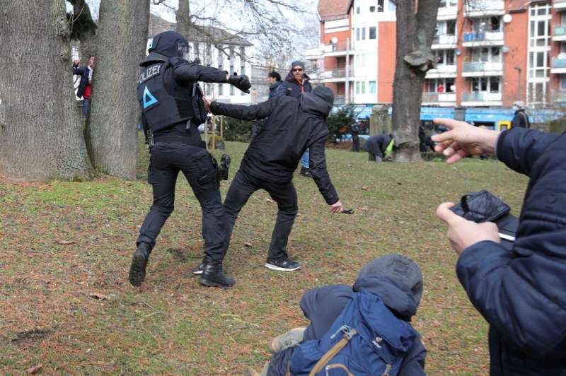 A protester and a policeman clash on the sidelines of an anti-Covid restriction demonstration in the German city of Kassel