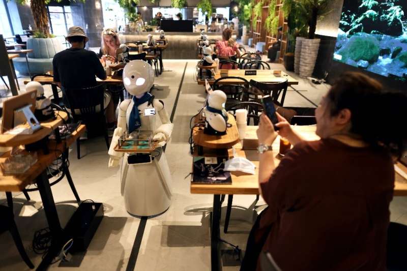 Around 20 miniature robots with almond-shaped eyes are dotted around the cafe