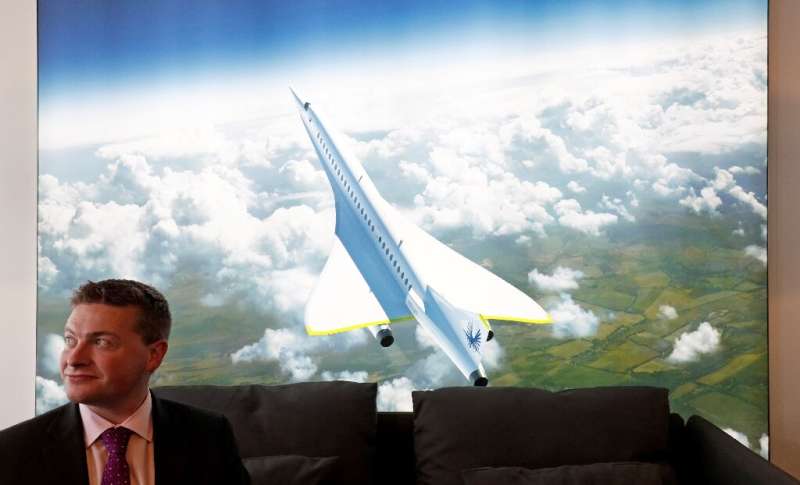 Boom Supersonic co-founder Blake Scholl is shown in 2018 in front of an artists impression of his company's proposed design for 
